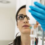 Kobieta w rękawiczkach sprawdza kroplówkę dla pacjenta z alergiami.