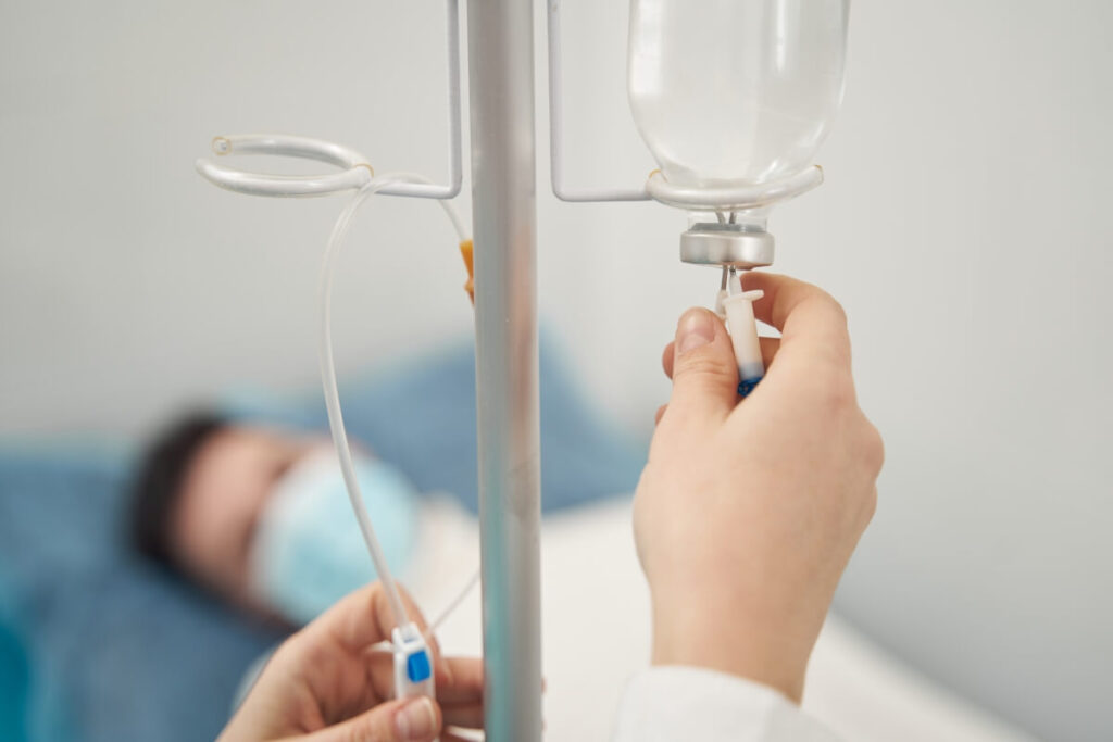Ręce regulujące kroplówkę, przewodnik w opiece nad pacjentem.